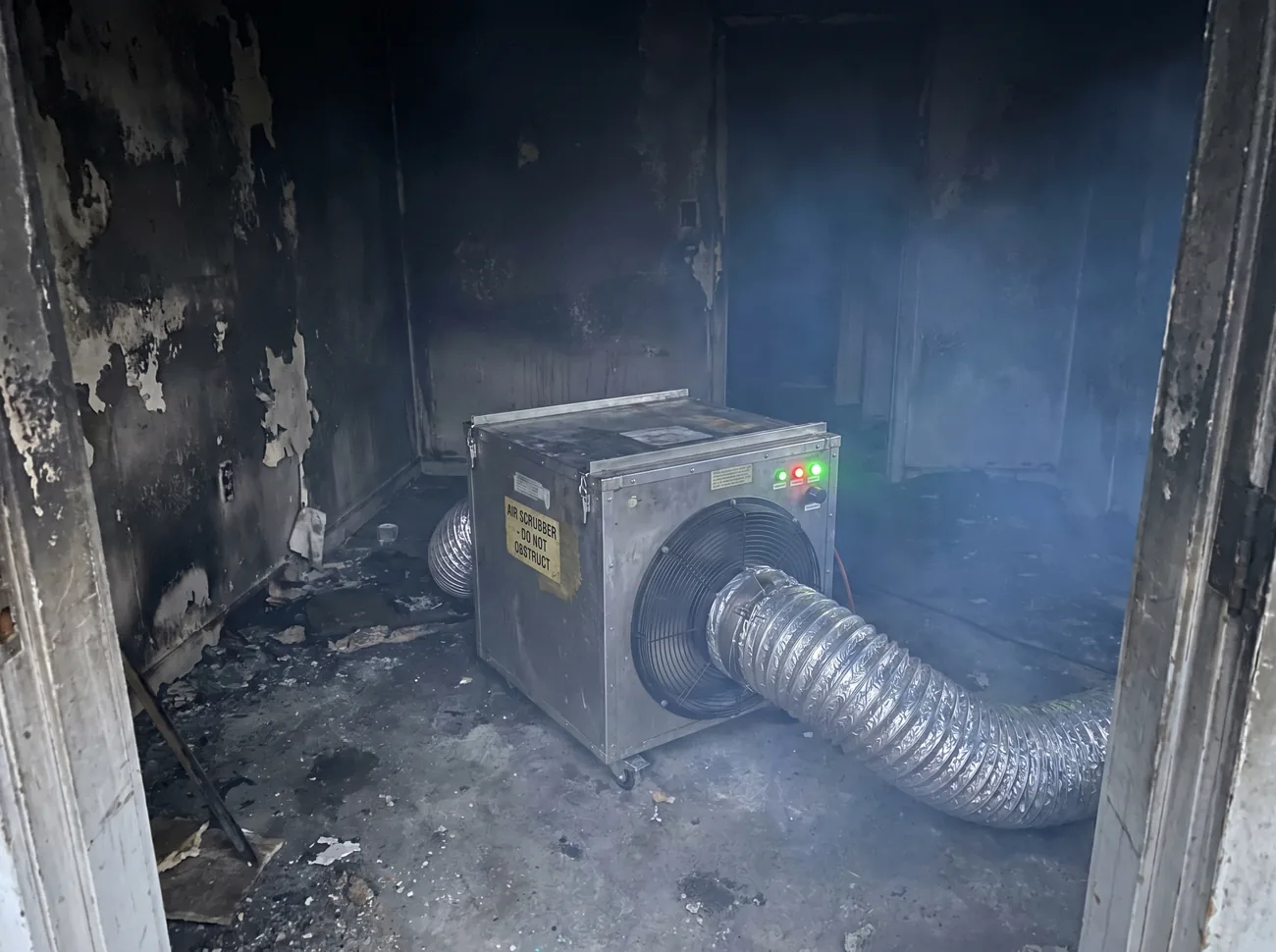 Commercial air scrubber and HEPA filtration unit running inside a fire-damaged Beaverton home
